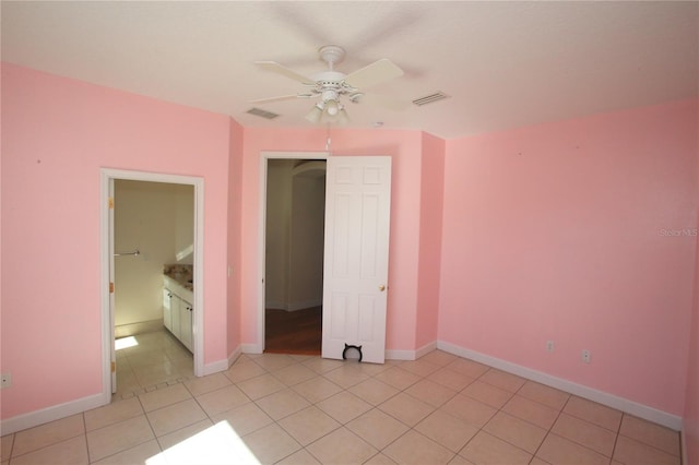 unfurnished bedroom featuring ceiling fan, ensuite bathroom, and light tile patterned floors