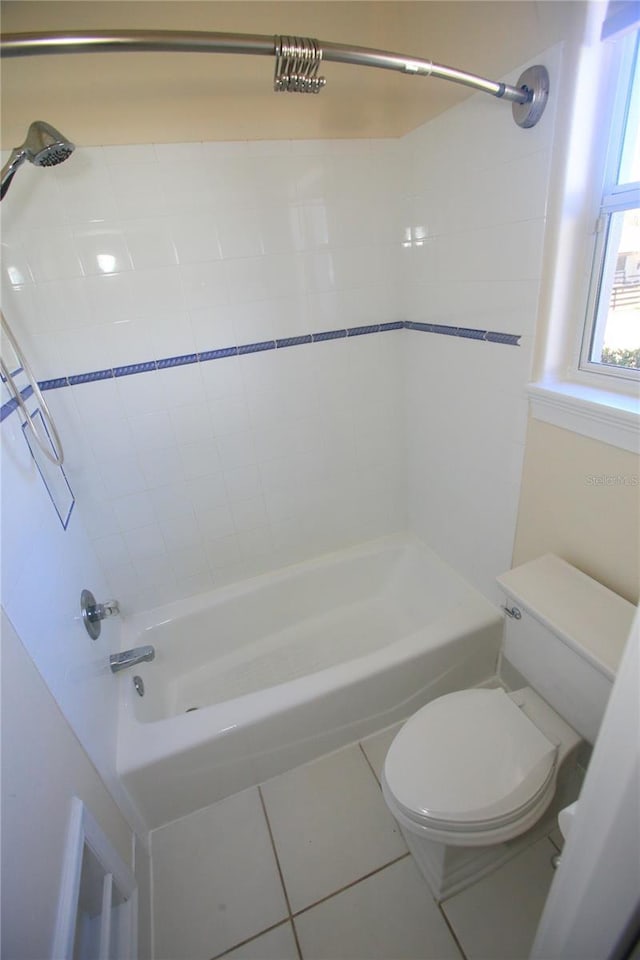 bathroom with toilet, tiled shower / bath combo, and tile patterned flooring