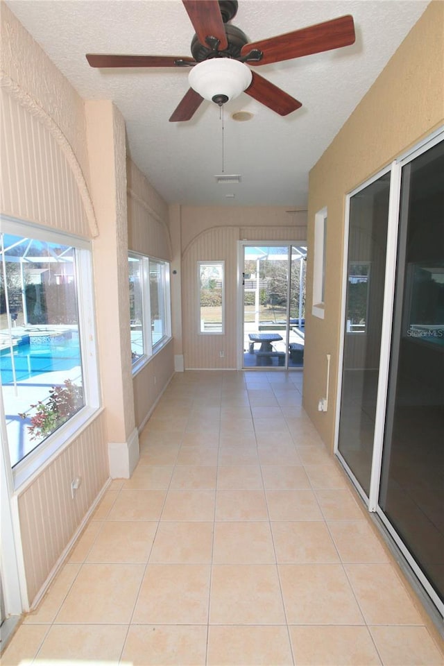 unfurnished sunroom with ceiling fan