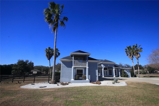 view of front facade with a balcony and a front yard