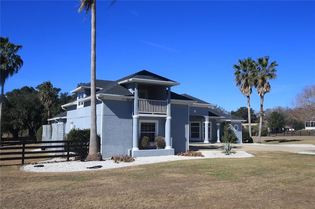 view of front of home featuring a balcony and a front lawn