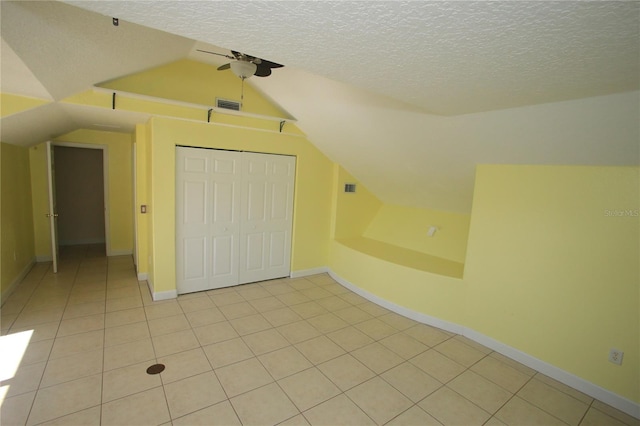 bonus room with lofted ceiling, a textured ceiling, and light tile patterned floors