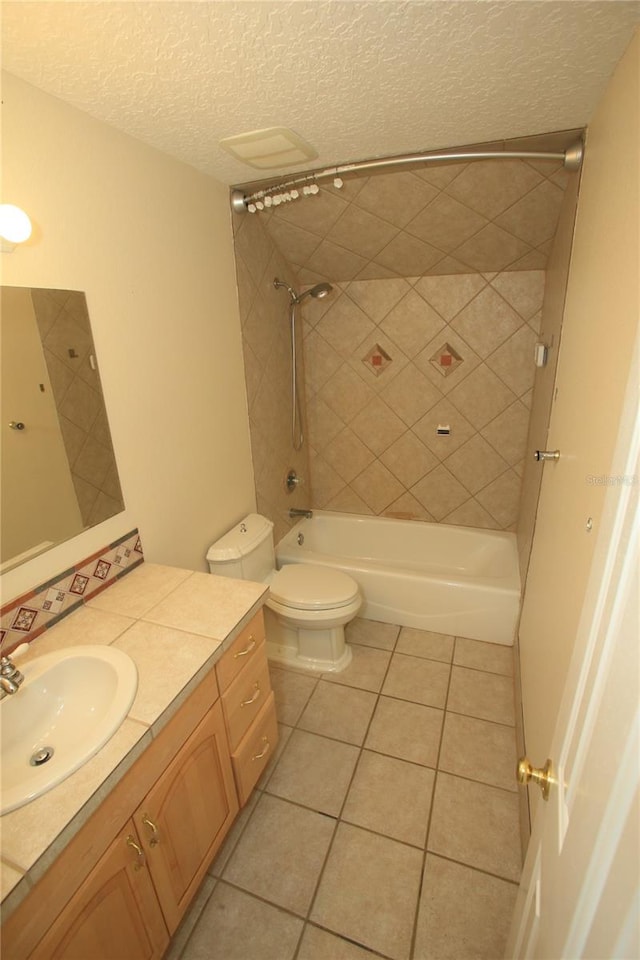 full bathroom with vanity, a textured ceiling, tile patterned floors, toilet, and tiled shower / bath