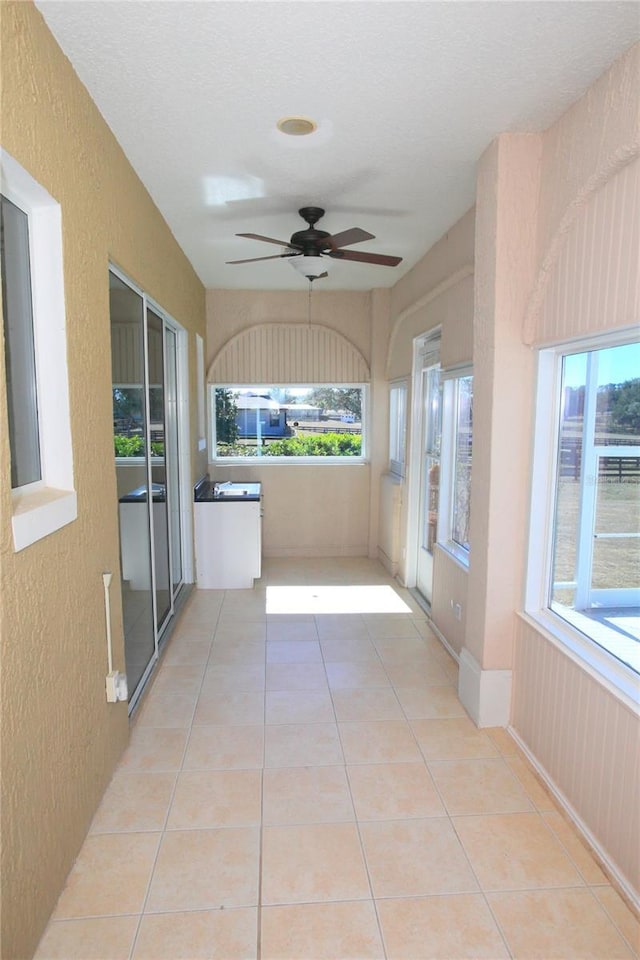 unfurnished sunroom with ceiling fan and plenty of natural light