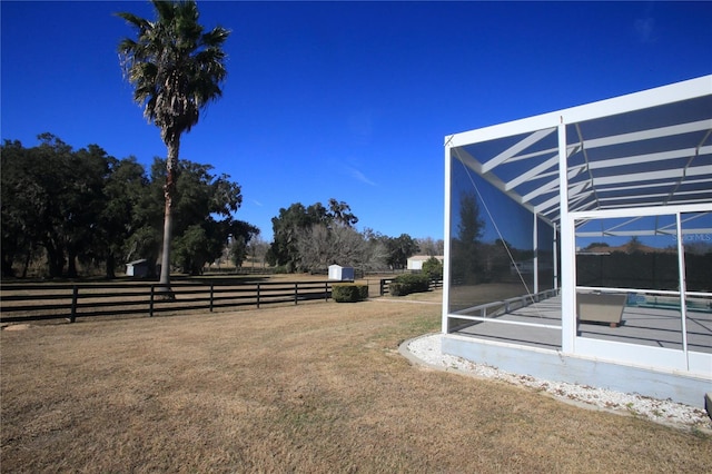 view of yard featuring a lanai, a swimming pool, and a rural view