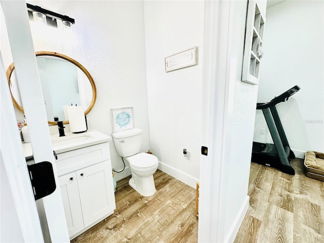 bathroom featuring toilet, wood-type flooring, and vanity