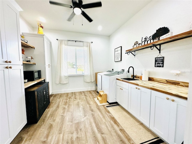 washroom featuring ceiling fan, light wood-type flooring, independent washer and dryer, cabinets, and sink