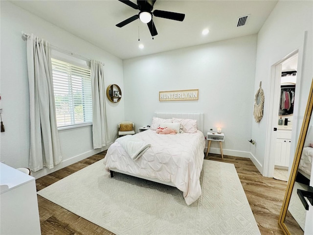 bedroom with a spacious closet, ceiling fan, a closet, and hardwood / wood-style flooring