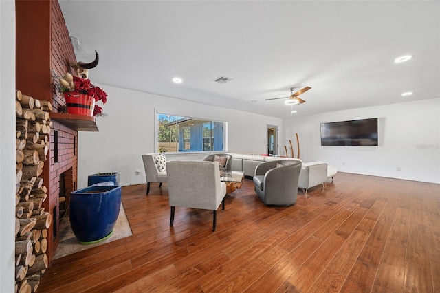 living room with ceiling fan, a fireplace, and hardwood / wood-style flooring