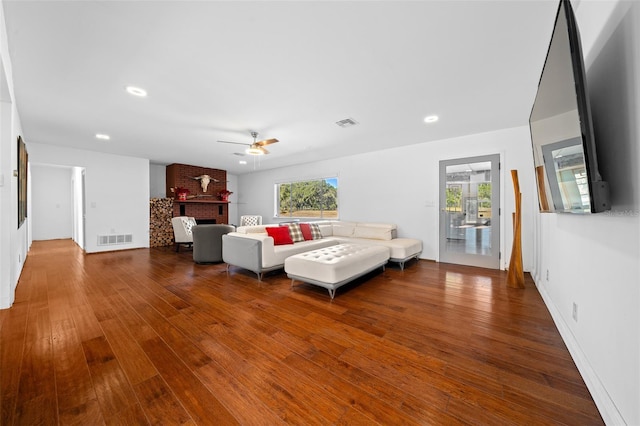 living room featuring ceiling fan, a fireplace, and hardwood / wood-style flooring