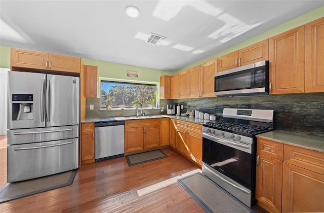 kitchen featuring dark wood-type flooring, sink, stainless steel appliances, and tasteful backsplash