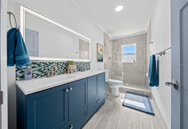 bathroom featuring vanity, backsplash, toilet, ornamental molding, and tiled shower