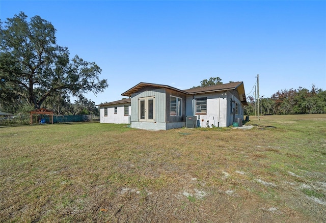 rear view of house featuring a lawn, french doors, and central AC