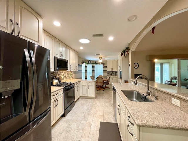 kitchen with black appliances, light stone countertops, sink, tasteful backsplash, and ceiling fan