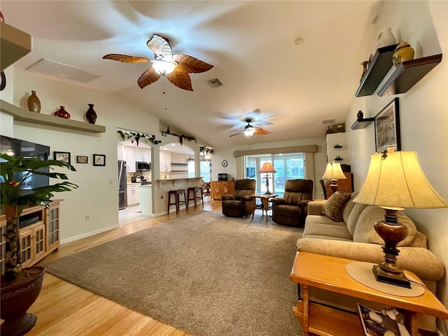 living room with ceiling fan, light wood-type flooring, and lofted ceiling