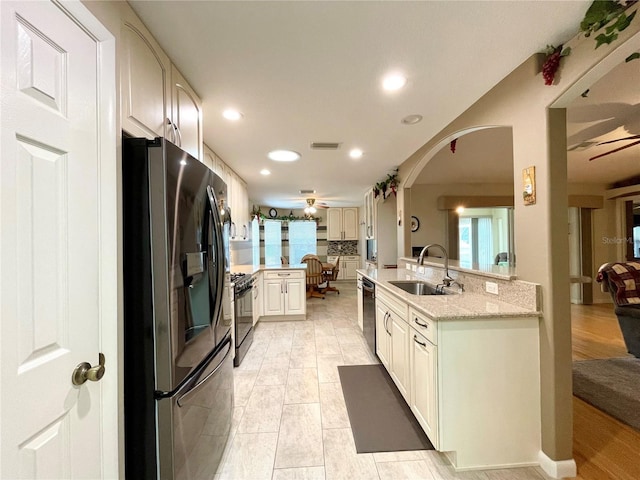 kitchen with dishwasher, light stone countertops, stainless steel fridge with ice dispenser, sink, and black gas range oven