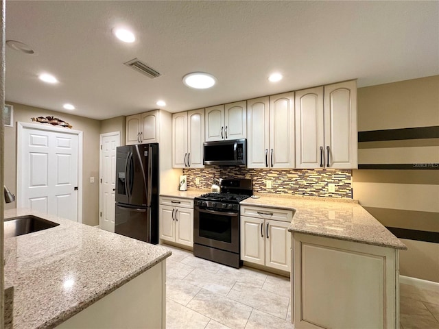 kitchen featuring gas range, sink, black refrigerator with ice dispenser, tasteful backsplash, and light stone counters