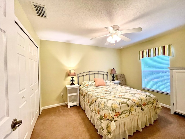 carpeted bedroom with ceiling fan, a textured ceiling, and a closet