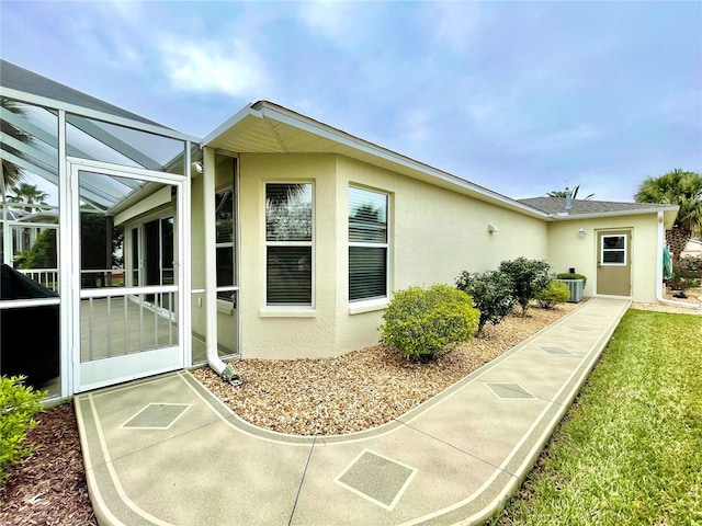 rear view of property featuring central AC unit and glass enclosure