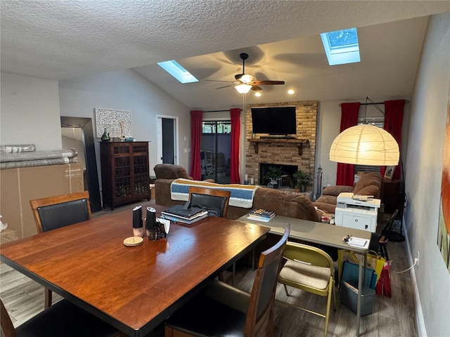 dining area with a textured ceiling, lofted ceiling, a fireplace, hardwood / wood-style flooring, and ceiling fan