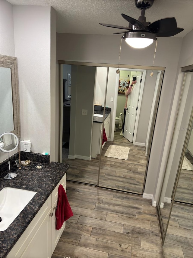 bathroom with ceiling fan, a textured ceiling, and vanity