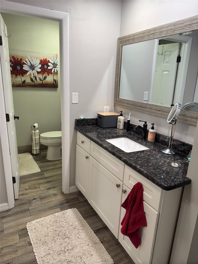 bathroom with hardwood / wood-style flooring, toilet, and vanity