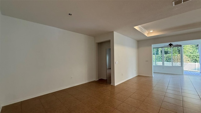 unfurnished room with light tile patterned floors, a tray ceiling, and ceiling fan