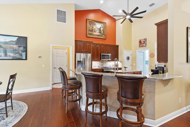 kitchen with light stone counters, a breakfast bar area, stainless steel appliances, and kitchen peninsula