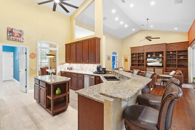 kitchen featuring sink, a breakfast bar area, stainless steel dishwasher, ceiling fan, and kitchen peninsula