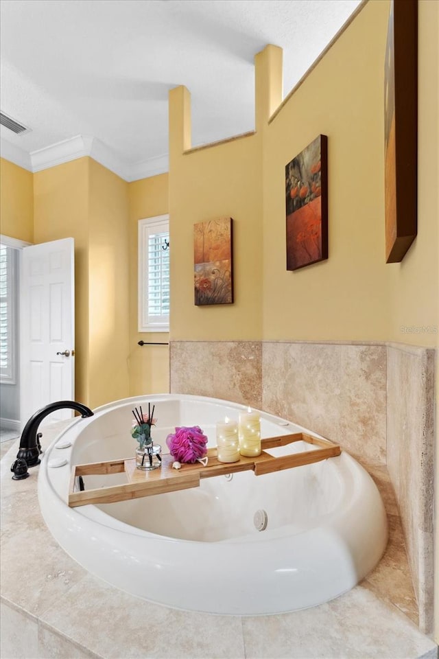 bathroom with a relaxing tiled tub and ornamental molding