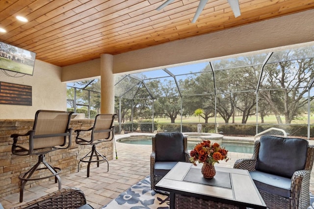 exterior space featuring a swimming pool with hot tub, a lanai, and a bar