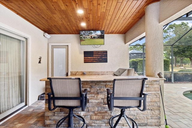 view of patio with a bar, an outdoor kitchen, grilling area, and a lanai