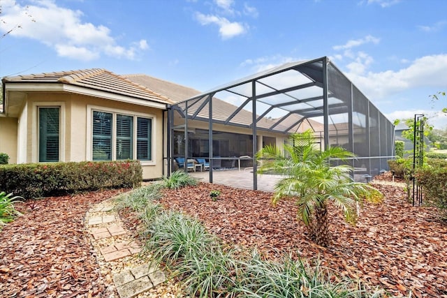 rear view of house featuring glass enclosure and a patio area