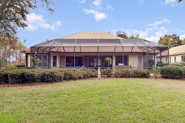 rear view of house with glass enclosure and a lawn