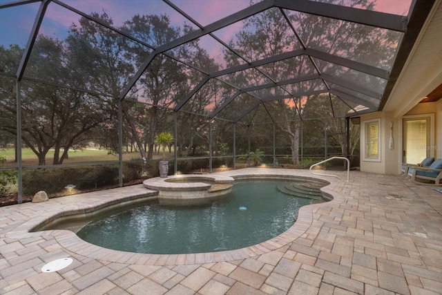 pool at dusk featuring a patio area, an in ground hot tub, and glass enclosure