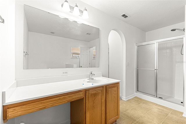 bathroom featuring vanity, a textured ceiling, and a shower with shower door