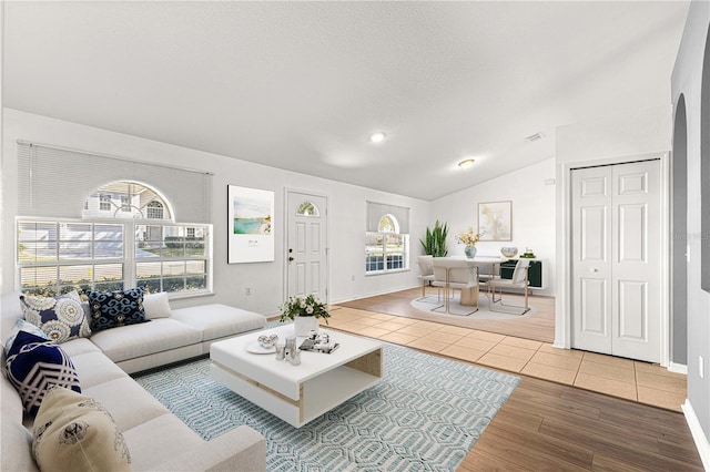 tiled living room featuring lofted ceiling and a textured ceiling