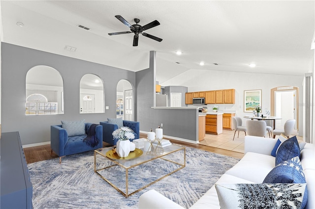 living room with vaulted ceiling, ceiling fan, and light hardwood / wood-style floors