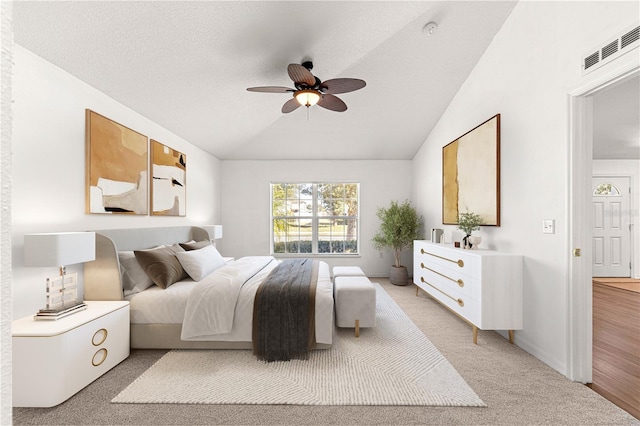 bedroom with lofted ceiling, a textured ceiling, light carpet, and ceiling fan