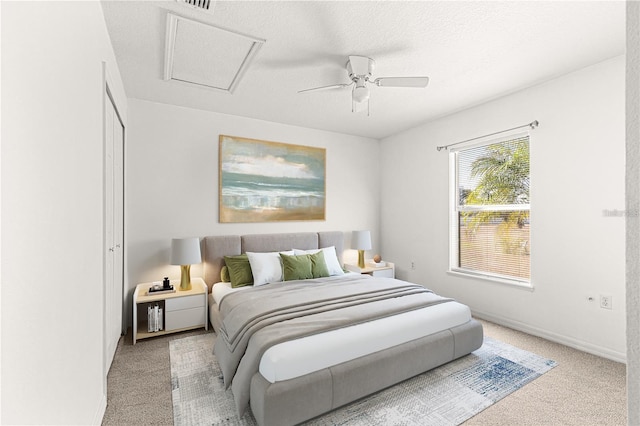 bedroom with ceiling fan, light colored carpet, and a textured ceiling