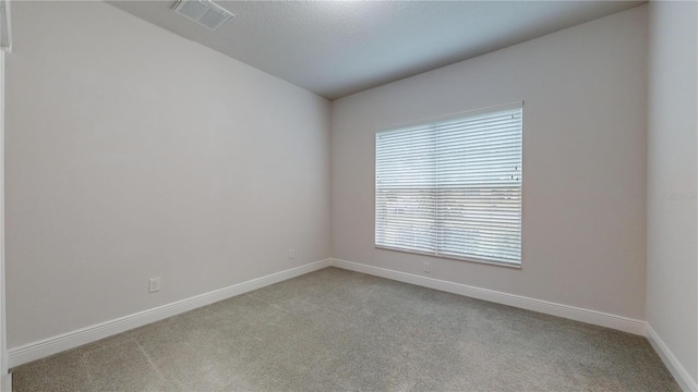 unfurnished room with light colored carpet and a textured ceiling