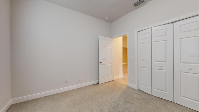 unfurnished bedroom featuring light colored carpet and a closet