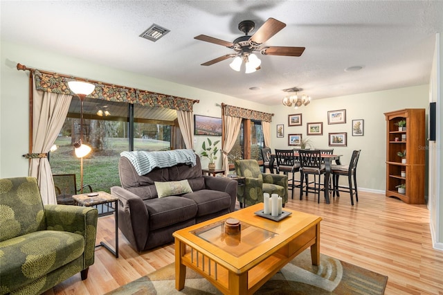 living room with ceiling fan with notable chandelier, a textured ceiling, and hardwood / wood-style flooring