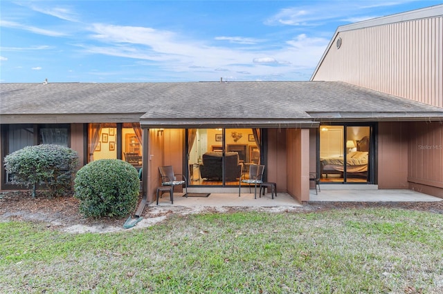 rear view of house featuring a lawn and a patio