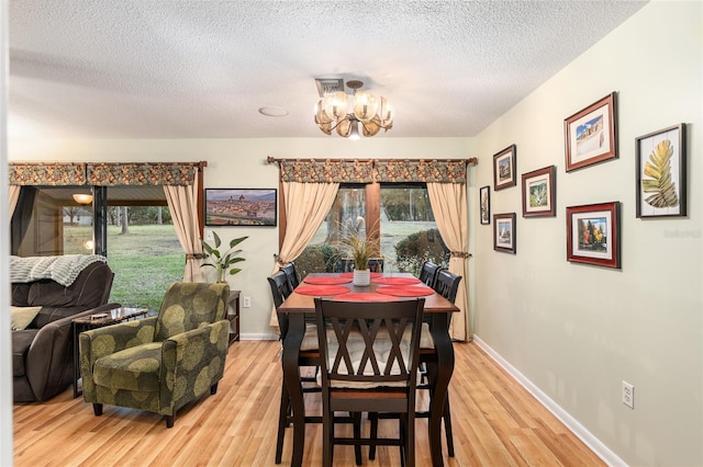 dining area with a textured ceiling, hardwood / wood-style floors, and an inviting chandelier