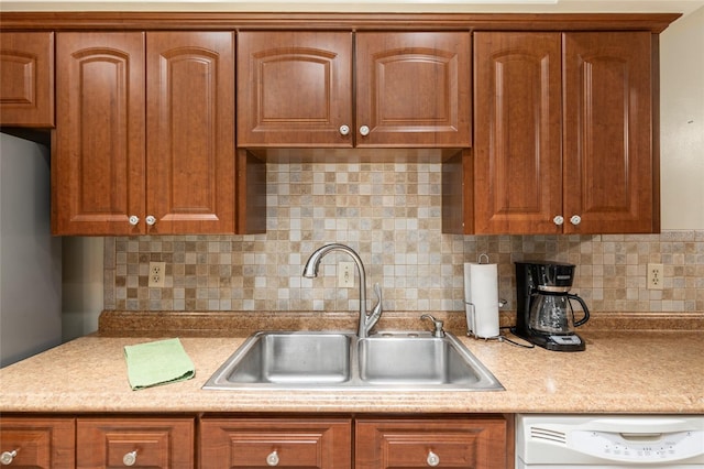 kitchen featuring decorative backsplash, sink, white dishwasher, and stainless steel refrigerator