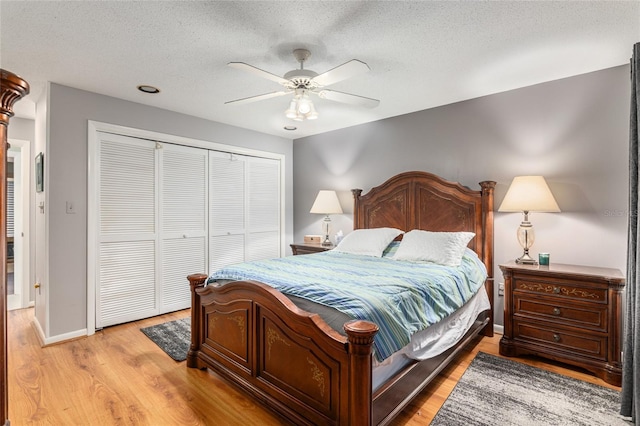 bedroom featuring a textured ceiling, ceiling fan, a closet, and light hardwood / wood-style floors