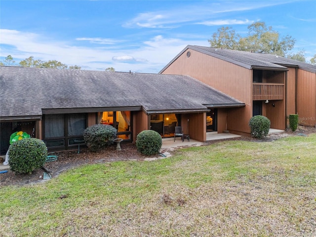 rear view of property with a balcony, a patio, and a yard