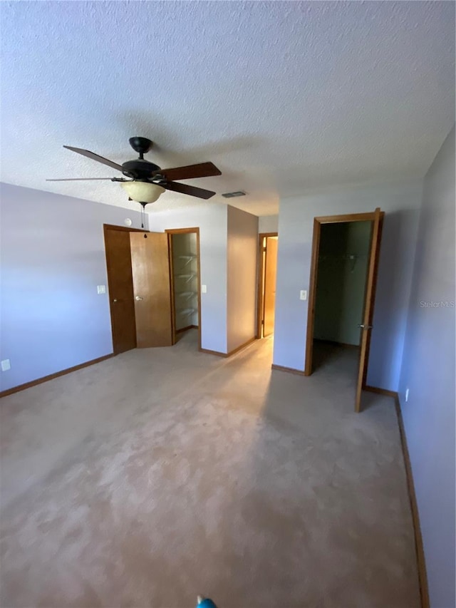 unfurnished room featuring a textured ceiling, ceiling fan, and carpet floors