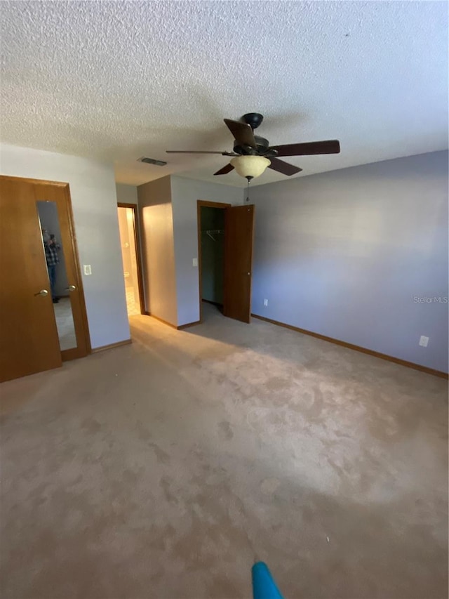 carpeted spare room featuring a textured ceiling and ceiling fan